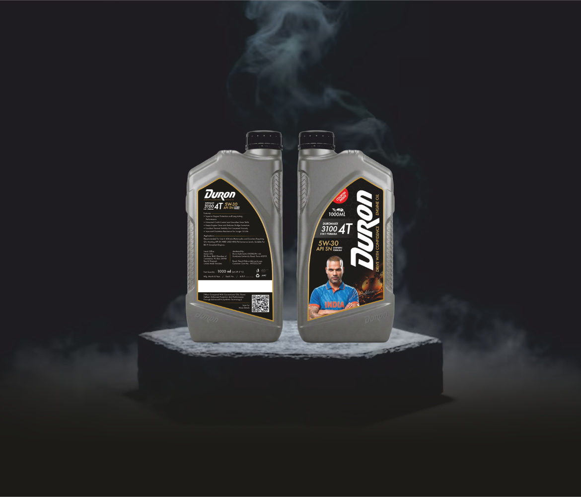 Duron 3100 4T 5W30 synthetic motorcycle engine oil, 1000ml grey bottles, with black cap front & back labels, cricketer image( Shikhar Dhawan in blue jersey ), QR code, black-gold design.
